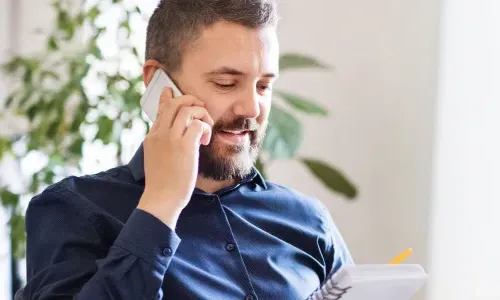 IT Manager Discussing Team Strategy On Phone In Office